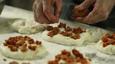manos de un panadero añadiendo pudín a la masa - primer plano