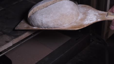 putting the bread dough into the oven with a wooden peel