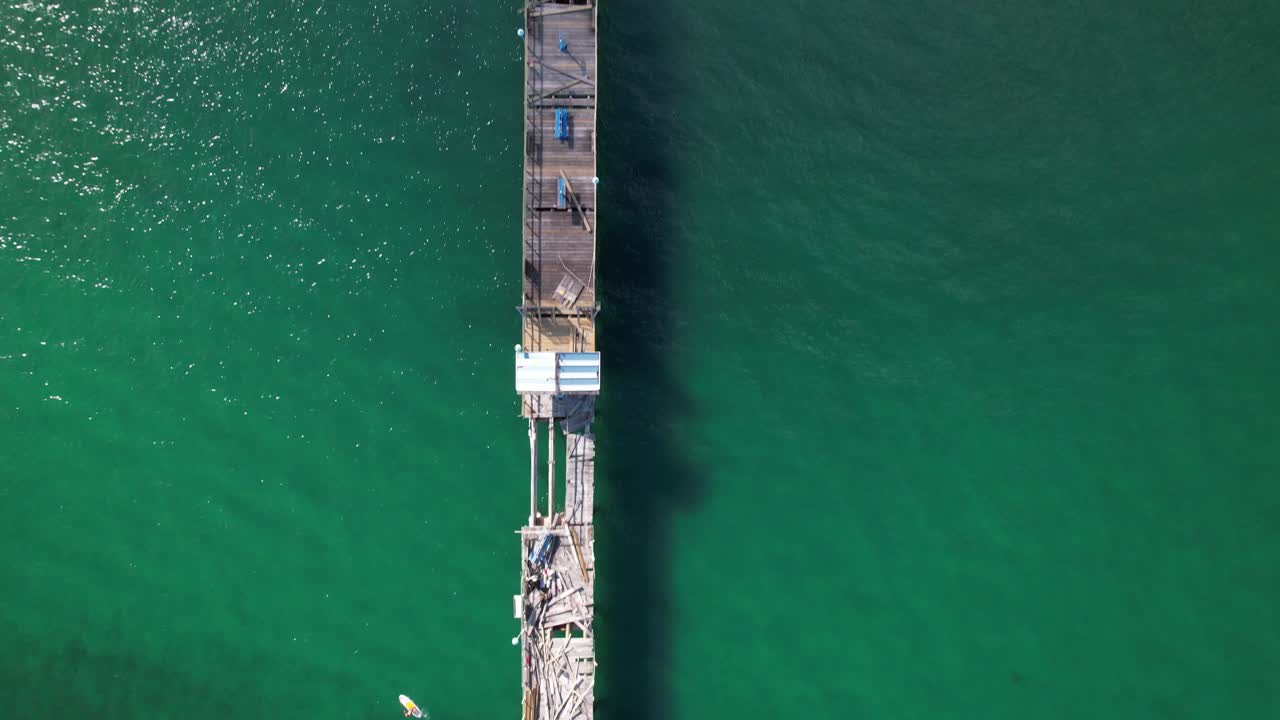 una vista de arriba hacia abajo sobre un muelle de madera en el océano en fort lauderdale, florida en un día soleado