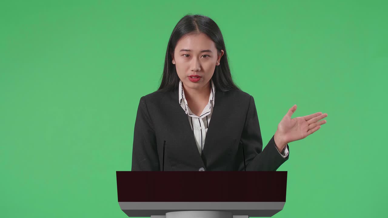 Asian Woman Of Organization Representative Pointing On Something While Speaking At A Press Conference In Government With Mock Up Green Screen
