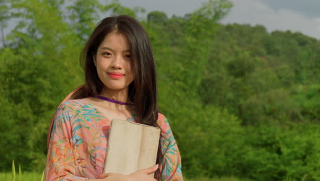 young woman female farmer standing in rice field plantation in traditional clothing hooding a tablet