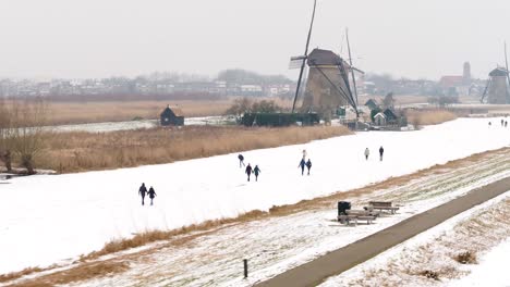 Winter-ice-skating-next-to-iconic-Dutch-windmills,-Kinderdijk