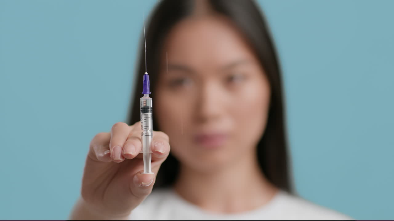 Woman holding syringe with a drop of liquid on the needle