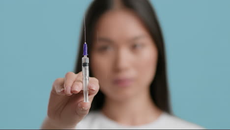 woman holding syringe with a drop of liquid on the needle