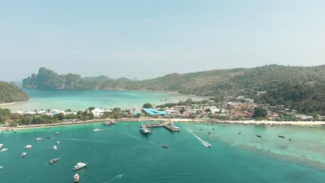 Top-view-of-Ton-Sai-Pier-busy-boat-traffic-and-Ton-Sai-Bay-Paradise-in-Ko-Phi-Phi-Don-Island,-Thailand---Aerial-Fly-over-shot