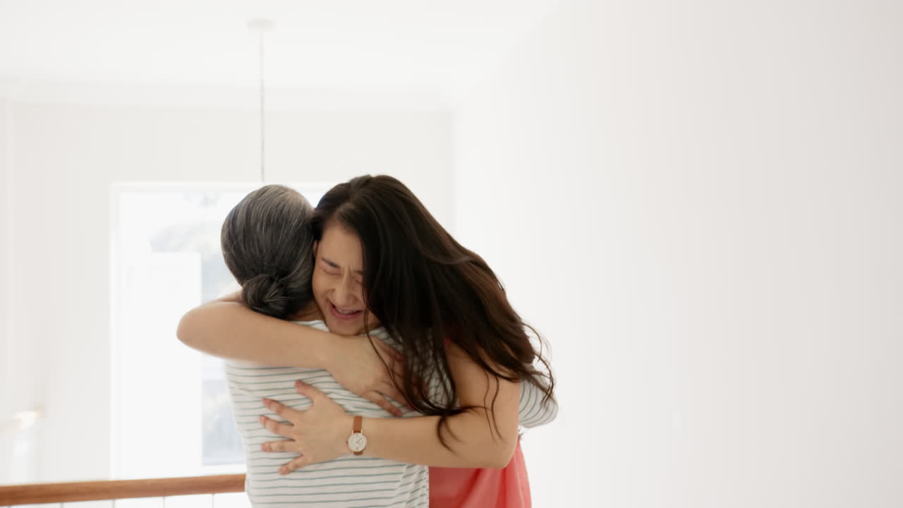Hugging each other, Asian grandmother and granddaughter sharing emotional moment inside home