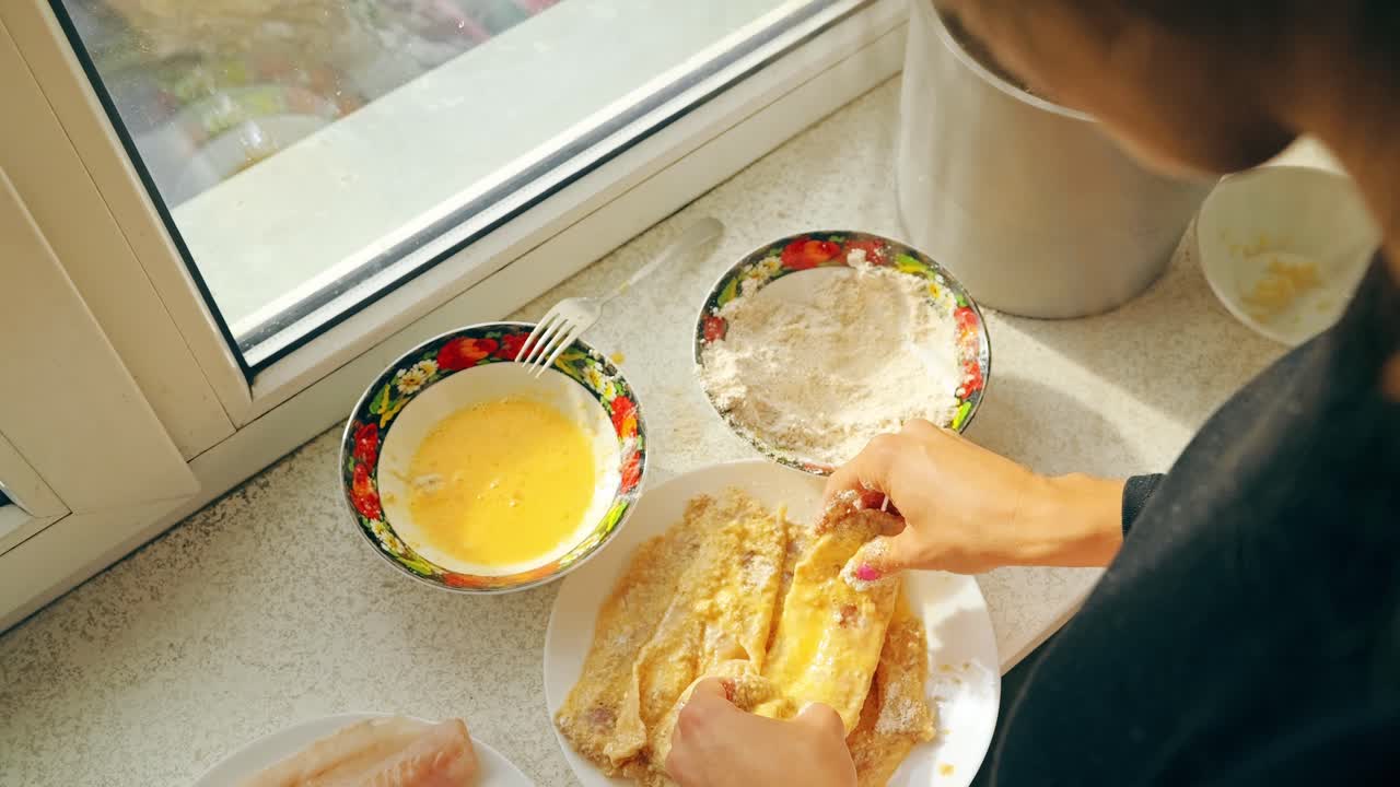 Woman preparing mintaj fish schnitzels with egg in slow motion kitchen dinner
