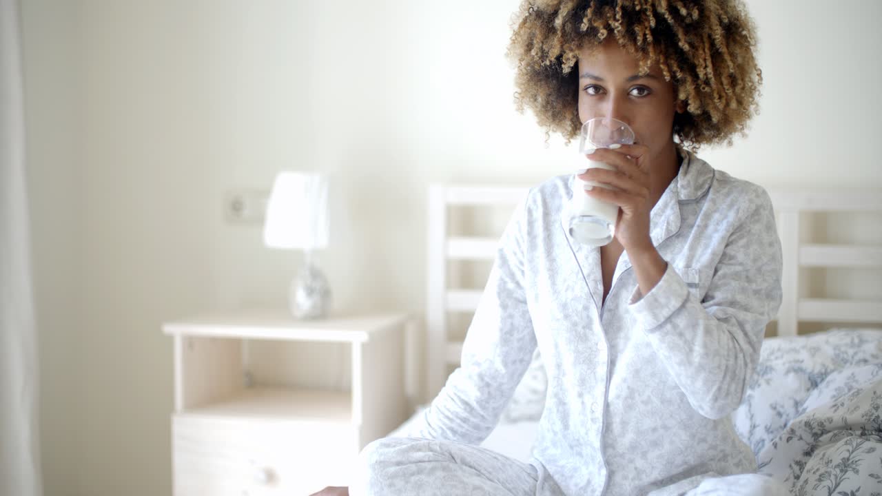 Donna che beve latte a letto.