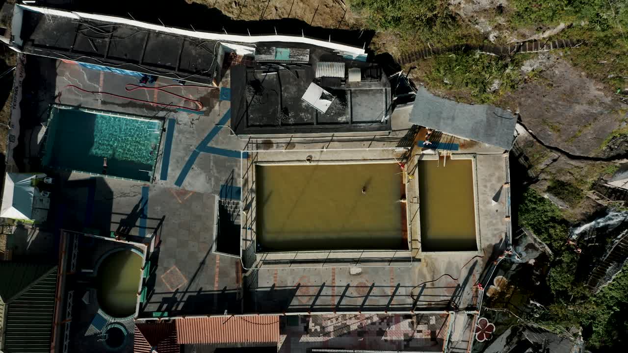 vista aérea del agua de las piscinas termales provenientes del volcán tungurahua y la cascada de virgen en baños, ecuador