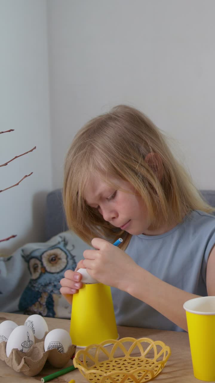 Bambina che decora un uovo di Pasqua con un pennarello a casa