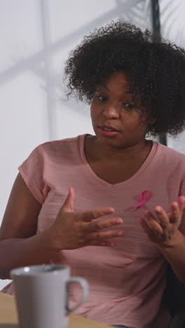 vertical video of mid adult woman wearing pink breast cancer awareness ribbon meeting and talking at therapy support group for cancer treatment patients with counsellor 3