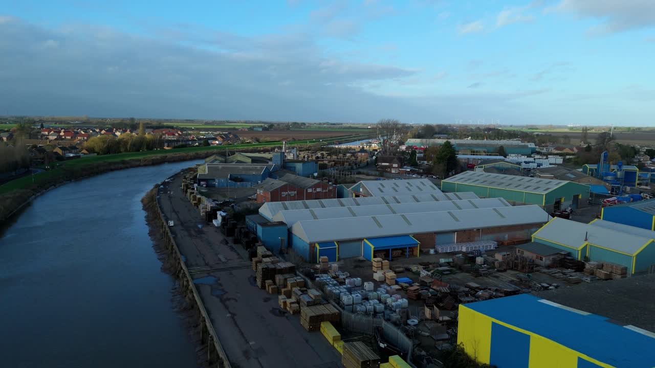 Luftaufnahme per Drohne von Binnenschifffahrtsgut bei Wisbech Wharf in Cambridgeshire, die industrielle Flussinfrastruktur und Lagerhallen hervorhebt.