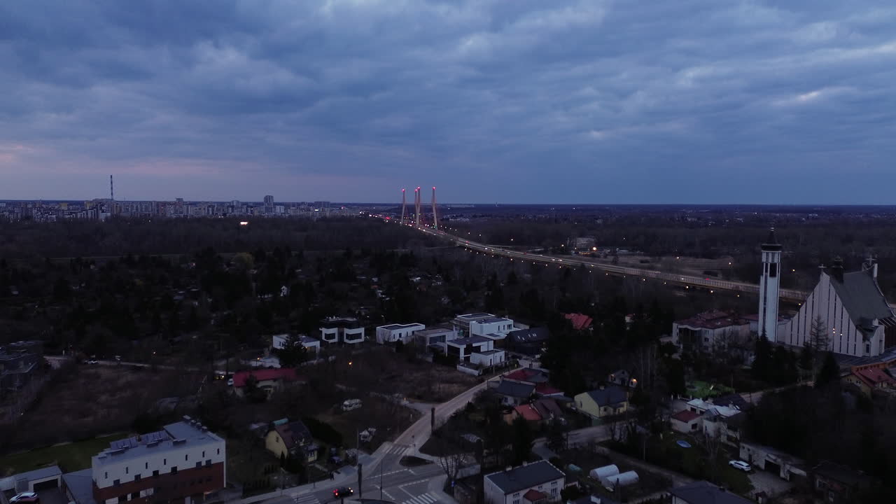 Aerial: Siekierki Bridge over the Vistula river at sunset with cityscape, skyscape and cloudy sky in Masovian, Poland, establishing drone shot