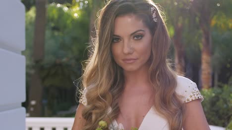 close up portrait of beautiful blonde bride with bouquet walking in sunny garden