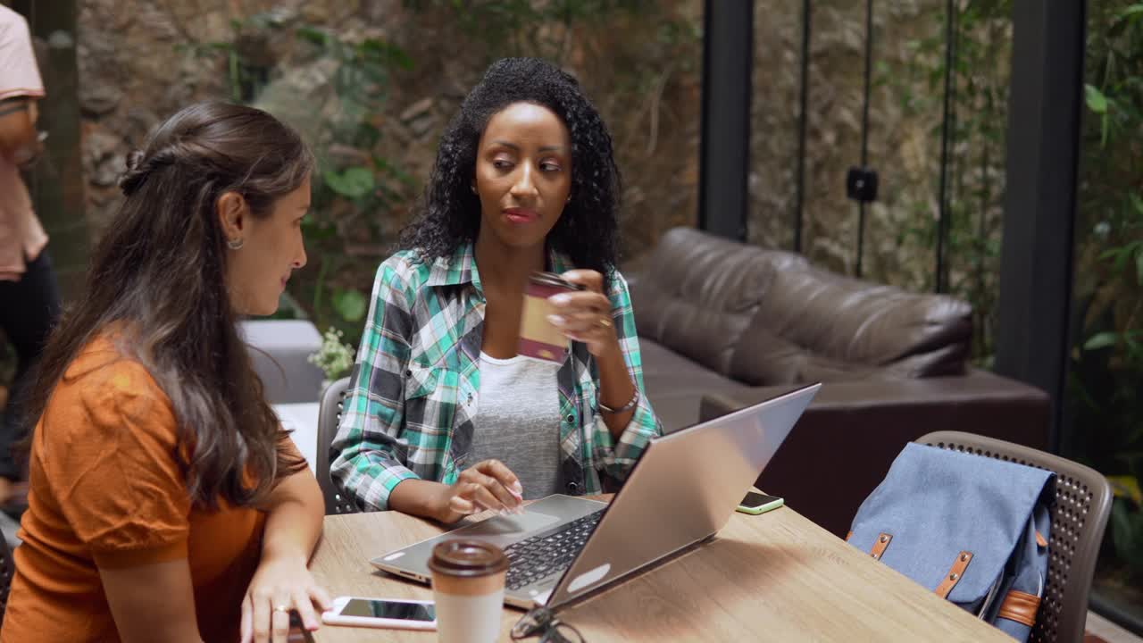 una mujer de negocios dando consejos a una mujer negra en un café.