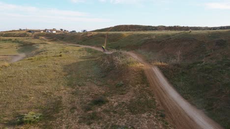 Toma-Aérea-De-Una-Pista-De-Motocross-Polvorienta-En-Málaga-En-España-Donde-Se-Corre-Una-Carrera-De-Motociclistas-Con-Acrobacias-Peligrosas-Sobre-Colinas-En-Un-Día-Soleado