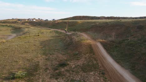 toma aérea de una pista de motocross polvorienta en málaga en españa donde se corre una carrera de motociclistas con acrobacias peligrosas sobre colinas en un día soleado