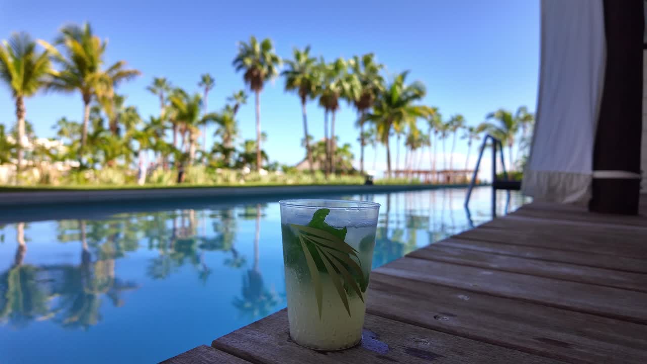 Poolside drink with a smoke bubble popping in slow motion.