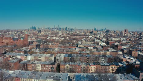 increíble toma aérea de drones de filas de apartamentos y edificios de viviendas de brooklyn, nueva york, con el horizonte de manhattan y la ciudad de nueva york en el fondo.