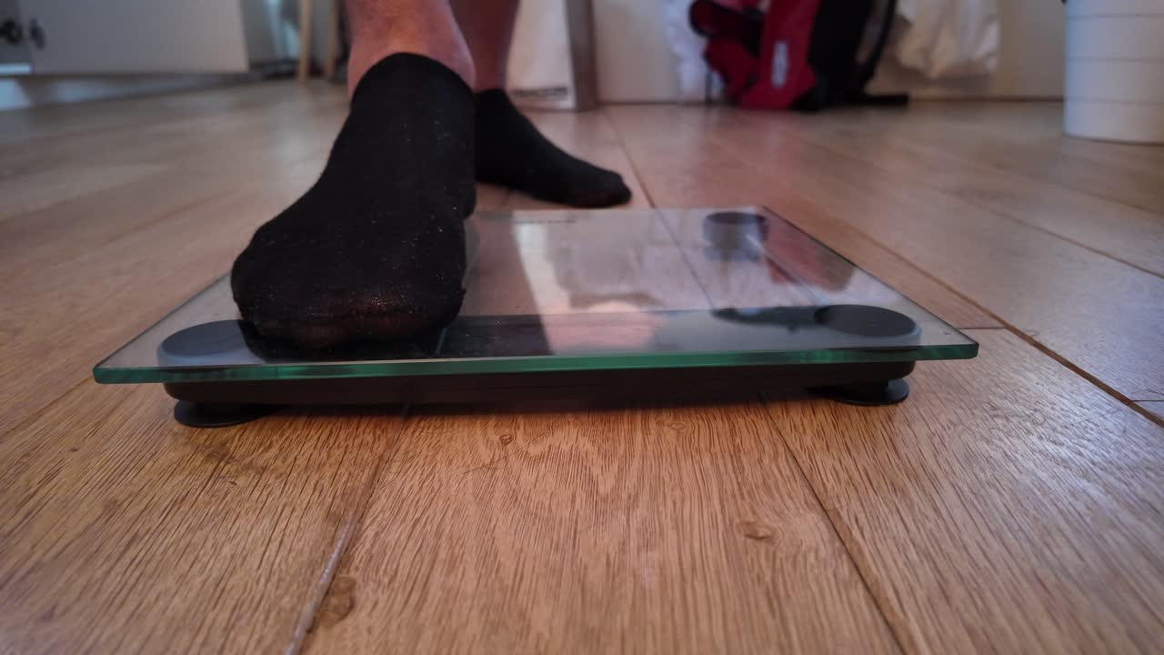 Person in black socks stepping on glass digital scale