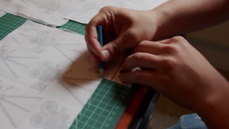 marking onto fabric on a cutting board using a blue marker. slow motion.