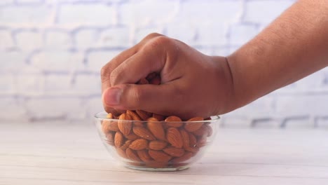 hand picking almonds from a glass bowl