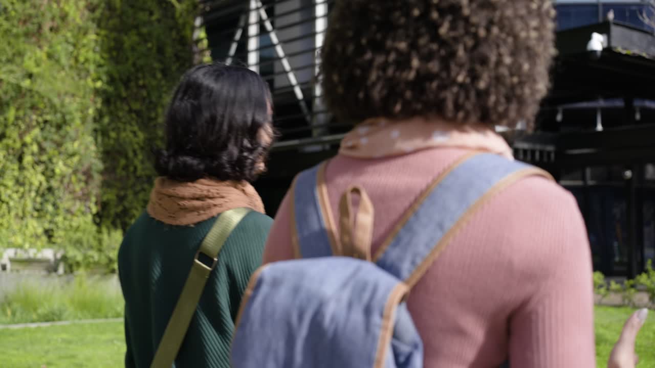 Amiche che camminano nel cortile, la donna con un maglione verde si volta innescando una conversazione sullo zaino.