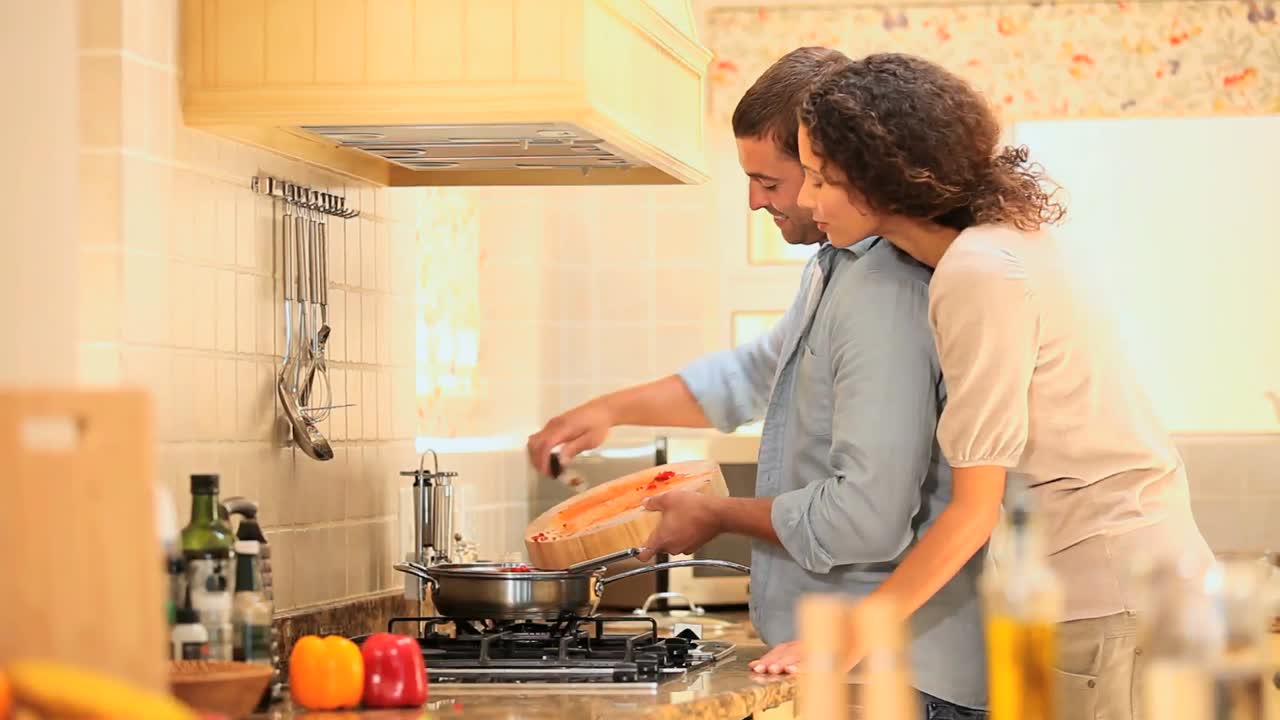 mulher jovem a ver o namorado a cozinhar.