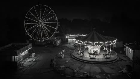 eerie beauty of an abandoned amusement park at night: a haunting look at a ferris wheel and carousel illuminated by ghostly lights