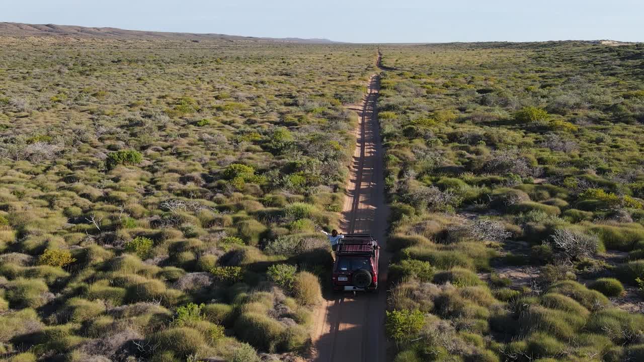 toma aérea que muestra a una mujer colgando de la ventana de un vehículo 4x4 y disfrutando del hermoso paisaje rural de australia
