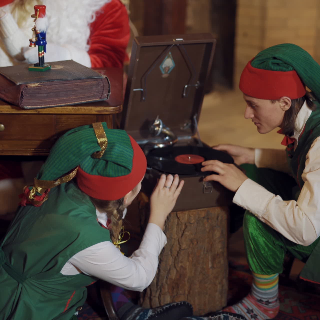 Curious elves with retro recorder indoors. Elves in festive costumes playing with old recorder with disks at Christmas.