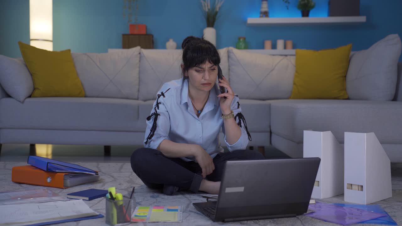 una trabajadora de oficina en casa recibe malas noticias por teléfono.