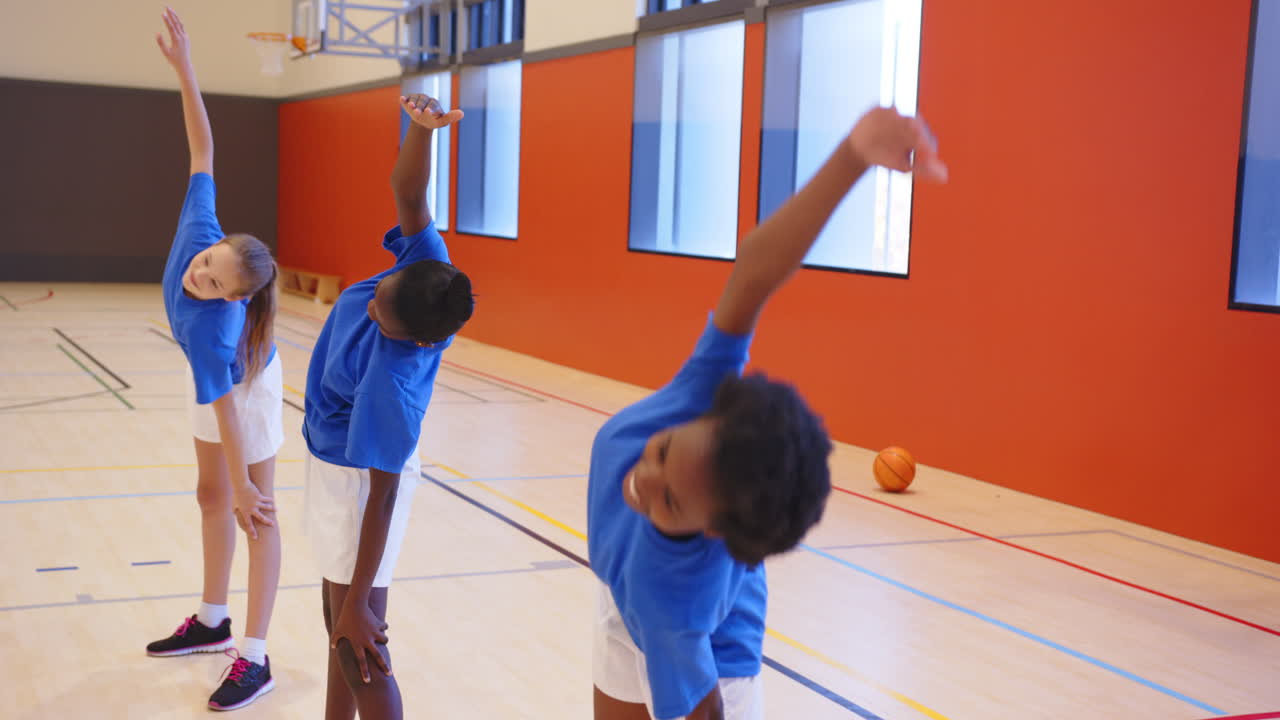 In de schoolgymzaal rekken en strekken meisjes tijdens de gymles.