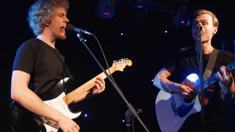 concert rock band performing on stage with two electric guitars singers. music video punk, heavy metal or rock group. slow motion instrument playing band of two men