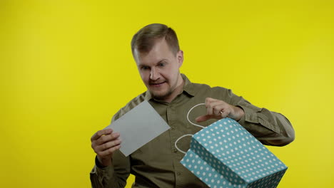 hombre mostrando la inscripción de la palabra de venta de la bolsa de compras, sonriendo, regocijándose descuentos en el viernes negro
