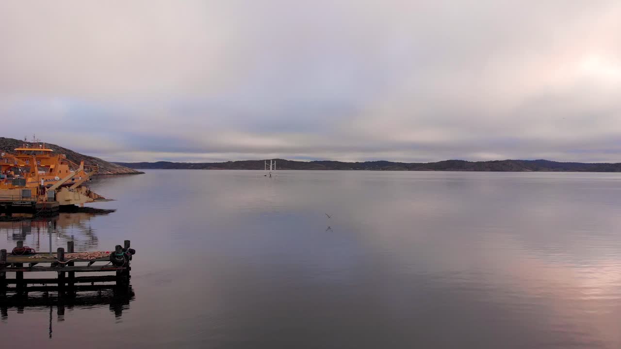 Birds flying over the waters by the peaceful fishing port of Lysekil, Sweden - low aerial