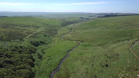 Weitwinkel-Luftaufnahme-Mit-Vorwärts--Und-Abwärtsbewegung,-Mit-Wistmans-Wald,-Einem-Fluss-Und-Grasbewachsenem-Moorland-Als-Kulisse