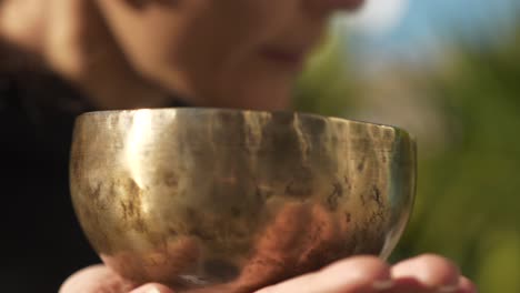 a yogi striking a singing bowl and listening to the sounds it projects