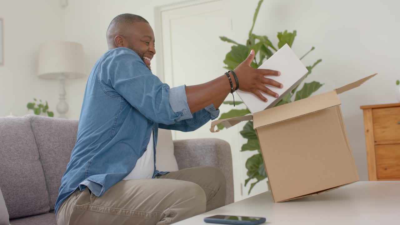 African American man seeing package at home lifting opening inspecting inner box checking order