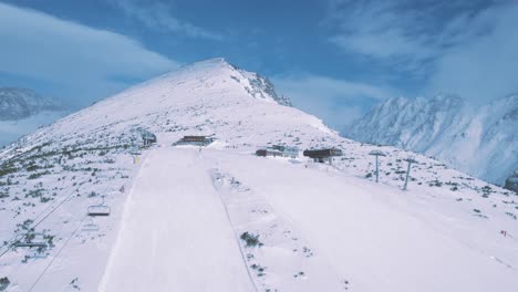 Magnificent-aerial-drone-view-rising-above-Tatra-National-Park-ski-piste-trail,-forward-reveals-stunning-snowy-mountain-landscape,-day