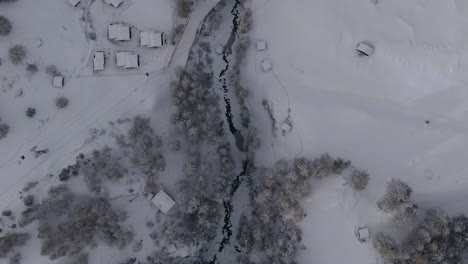 Scenic-cinematic-aerial-drone-of-river-at-Zermatt-Switzerlands-town-snow-cover-mountain-Matterhorn-October-November-heavy-fresh-snowfall-already-winter-on-climbing-peak-follow-top-down-movement