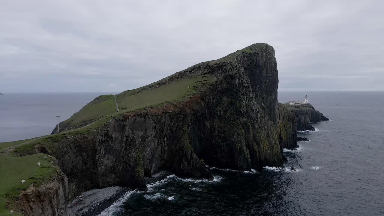 imágenes aéreas de drones de 4k que se acercan a los acantilados de neist point con faro en escocia, reino unido y ovejas en la hierba