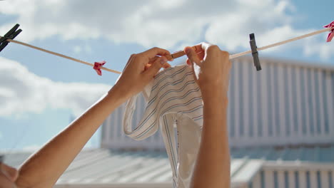 Closeup-hands-hang-bra-at-beach-house.-Vertically-stylish-beachwear-air-drying