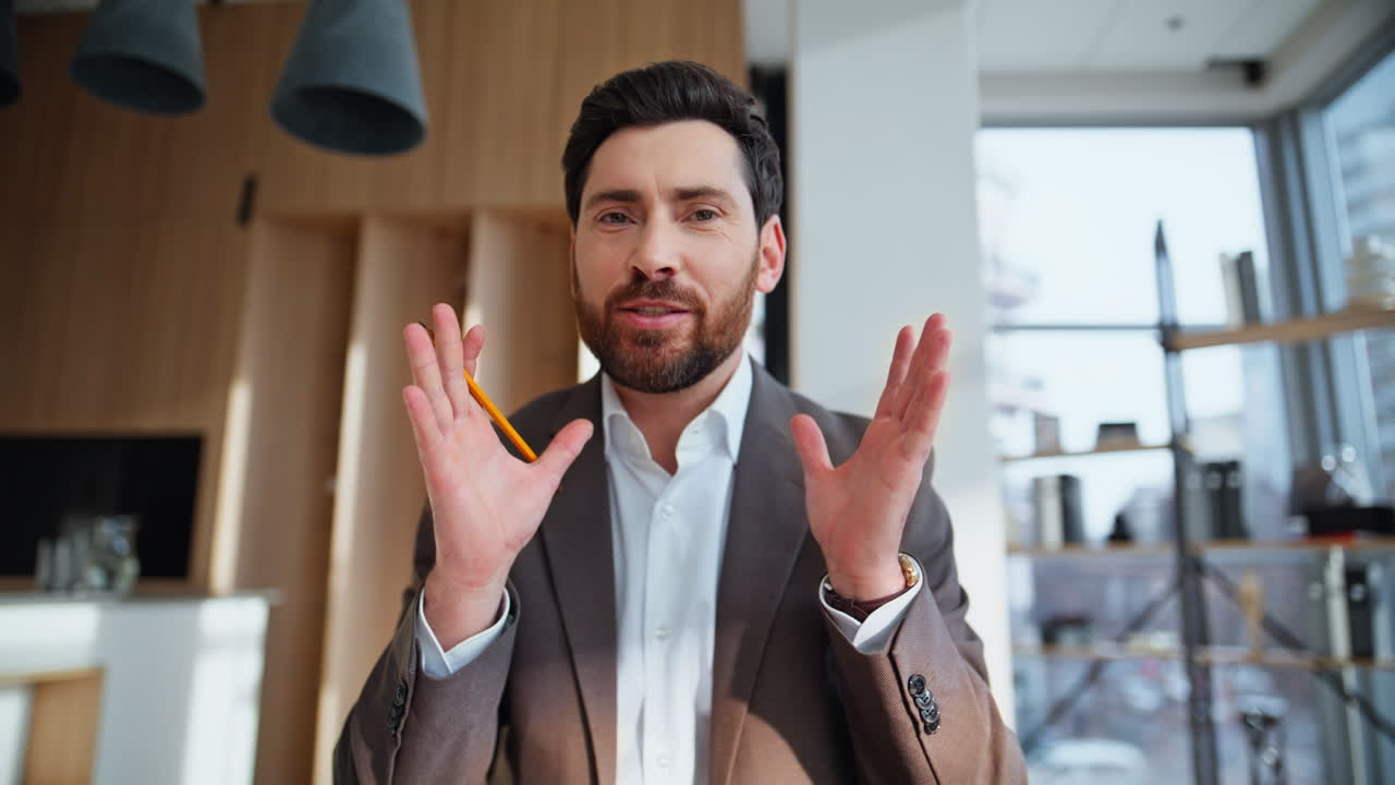Primo piano di un consulente finanziario sorridente in videochiamata dal suo ufficio.