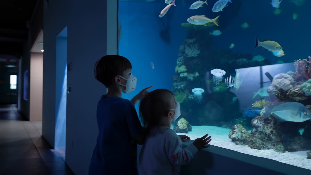 水族館で魚やクラゲを見るマスク姿の子供たち