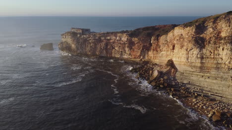 aerial view of nazare lighthouse and rocks in portugal at sunset