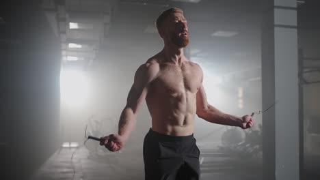 portrait of young male athlete skipping rope. slow motion male athlete exercising with jump rope in a gym.