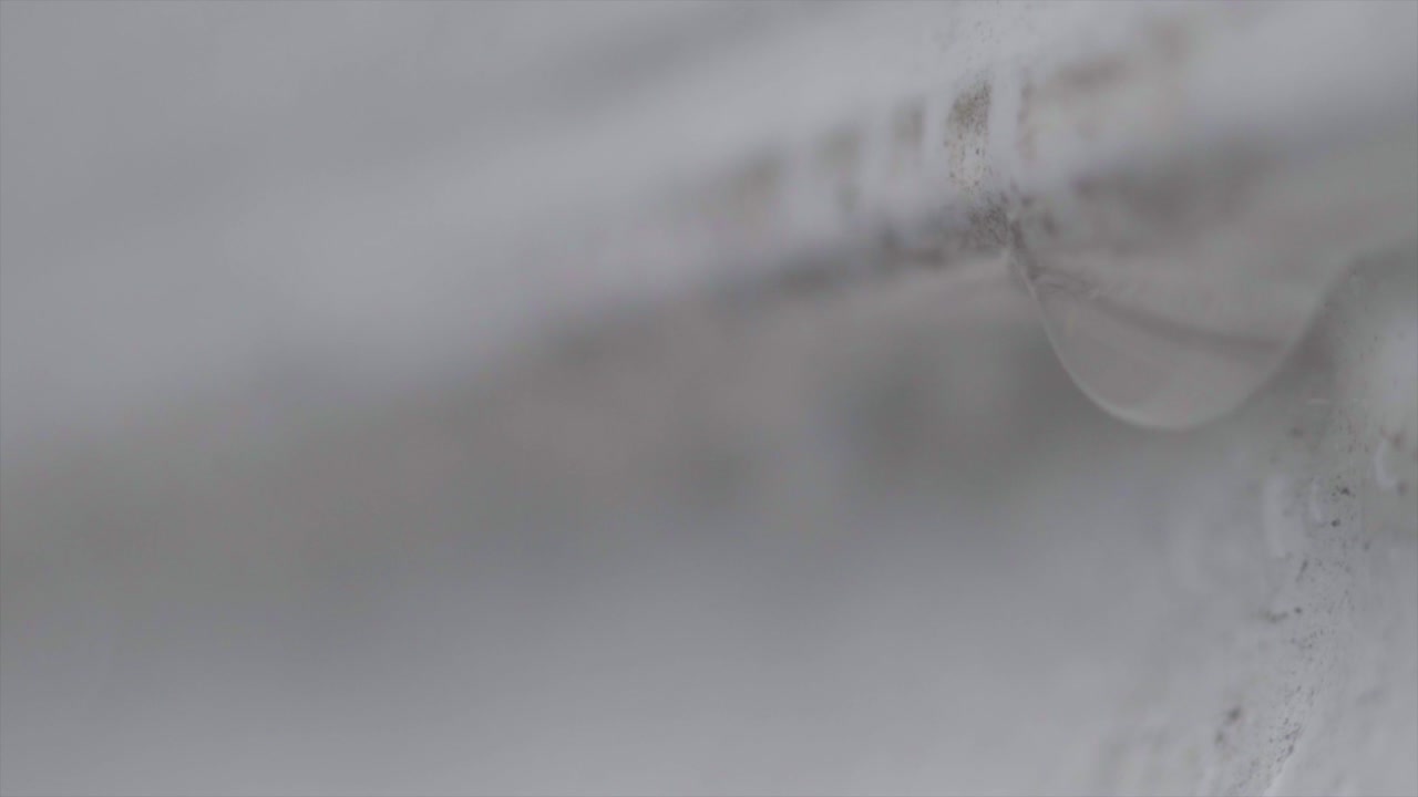 흰 벽에서 물방울이 떨어지는 매크로 샷