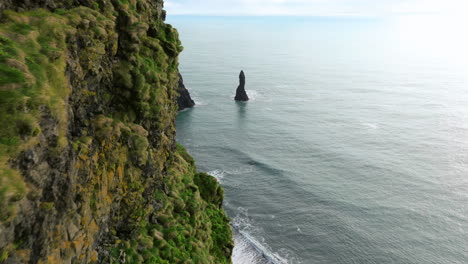 acantilados rocosos cubiertos de musgo en la playa de arena negra de reynisfjara en el sur de islandia