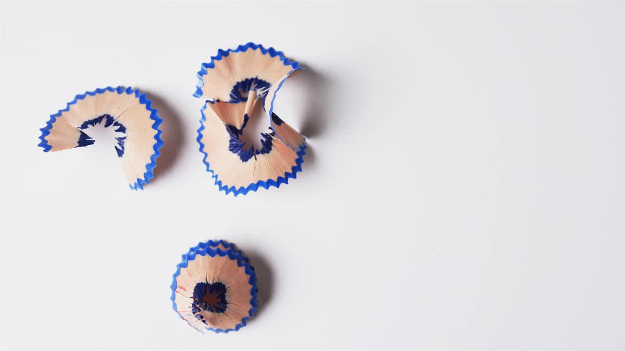 vista aérea de las virutas de lápiz azul con espacio de copia en fondo blanco, en cámara lenta